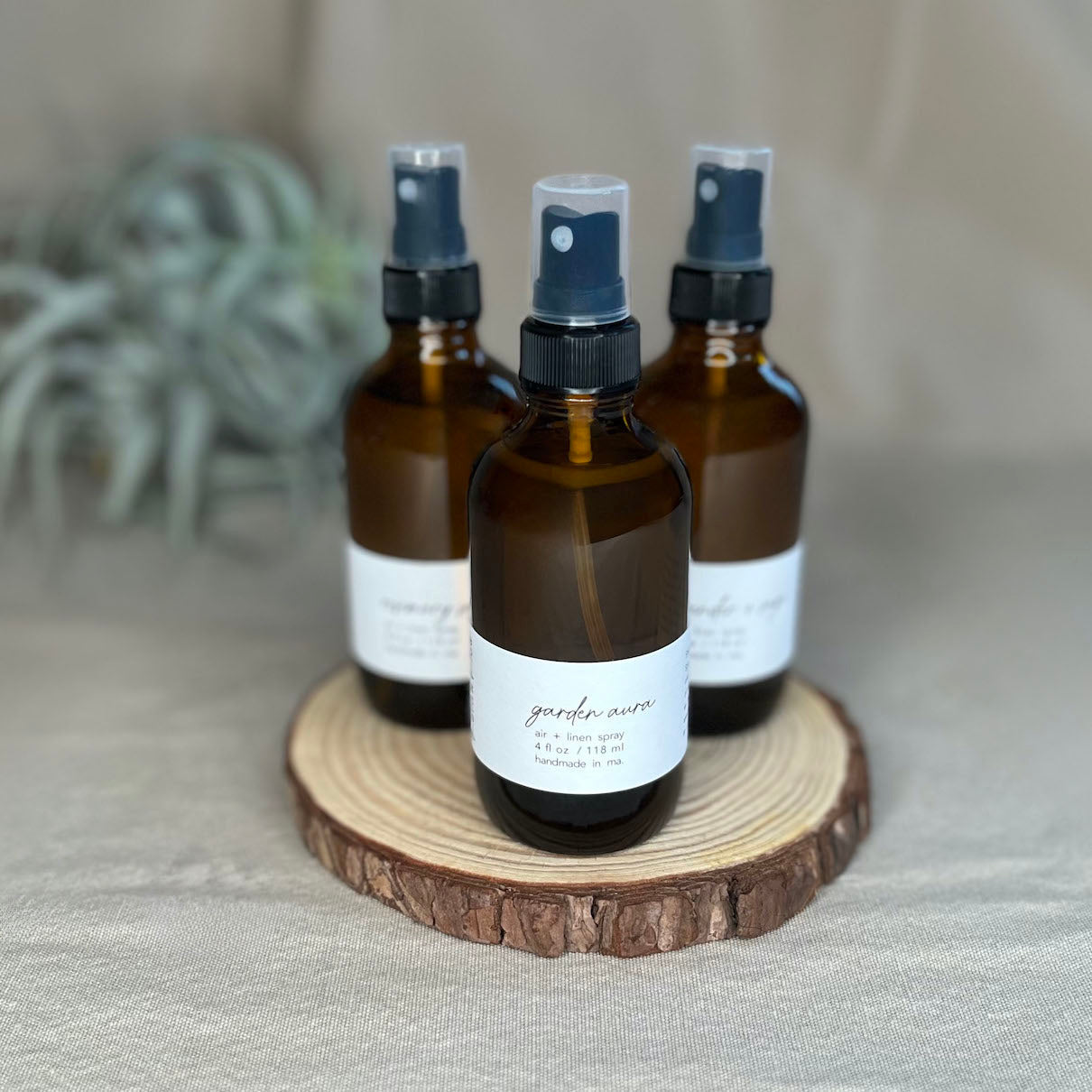 Fern x Flow natural and vegan Air + Linen sprays on a rustic wooden riser.