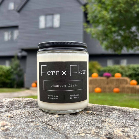 Fern x Flow Sleepy Hollow Halloween scented soy candle with a black and white label in front of The Salem Witch House in Salem MA