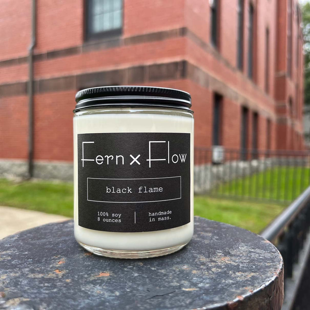 
                  
                    Fern x Flow Black Flame Halloween scented soy candle in front of brick building in Salem, MA
                  
                