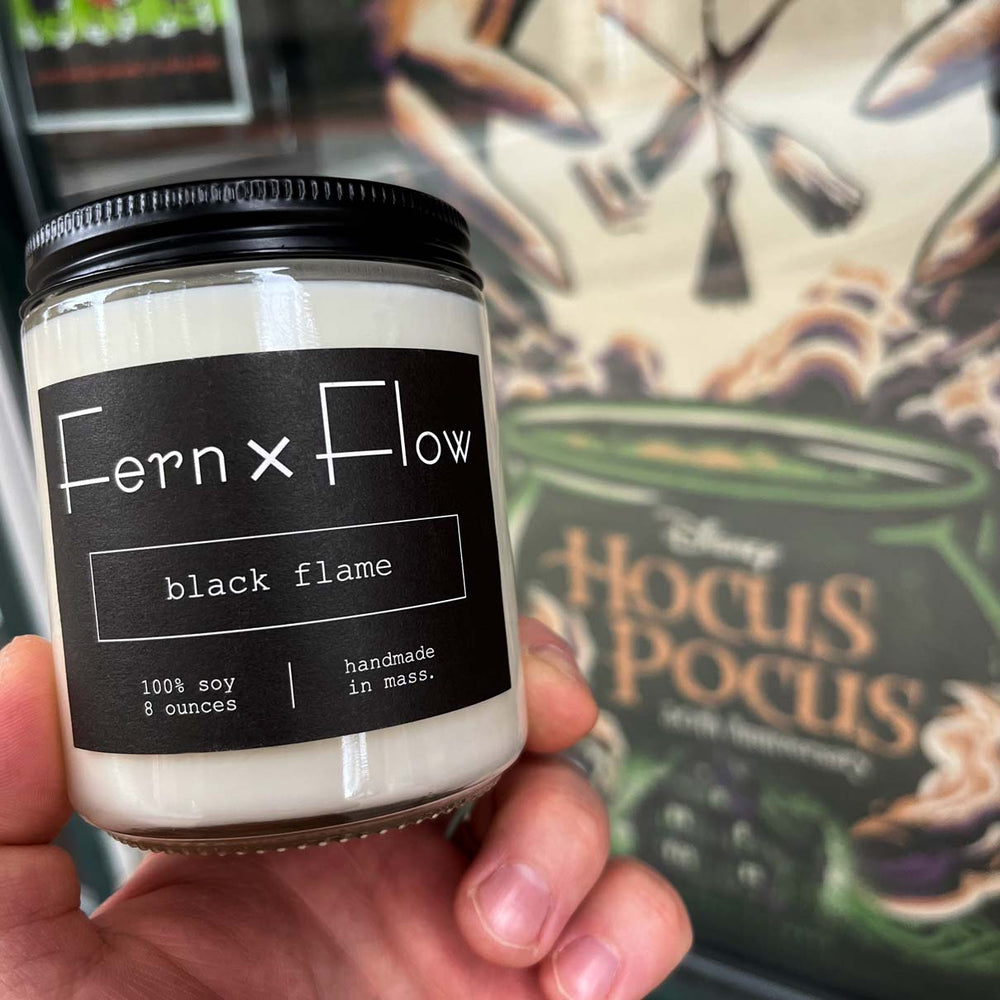 
                  
                    Fern x Flow Black Flame Hocus Pocus-inspired soy candle in front of Hocus Pocus movie poster in Salem, MA
                  
                