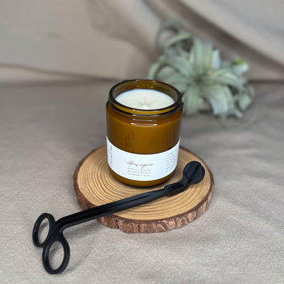 Eight-ounce Fern x Flow Citrus Agave scented soy candle with black matte wick trimmers in the foreground and an air plant in the background.