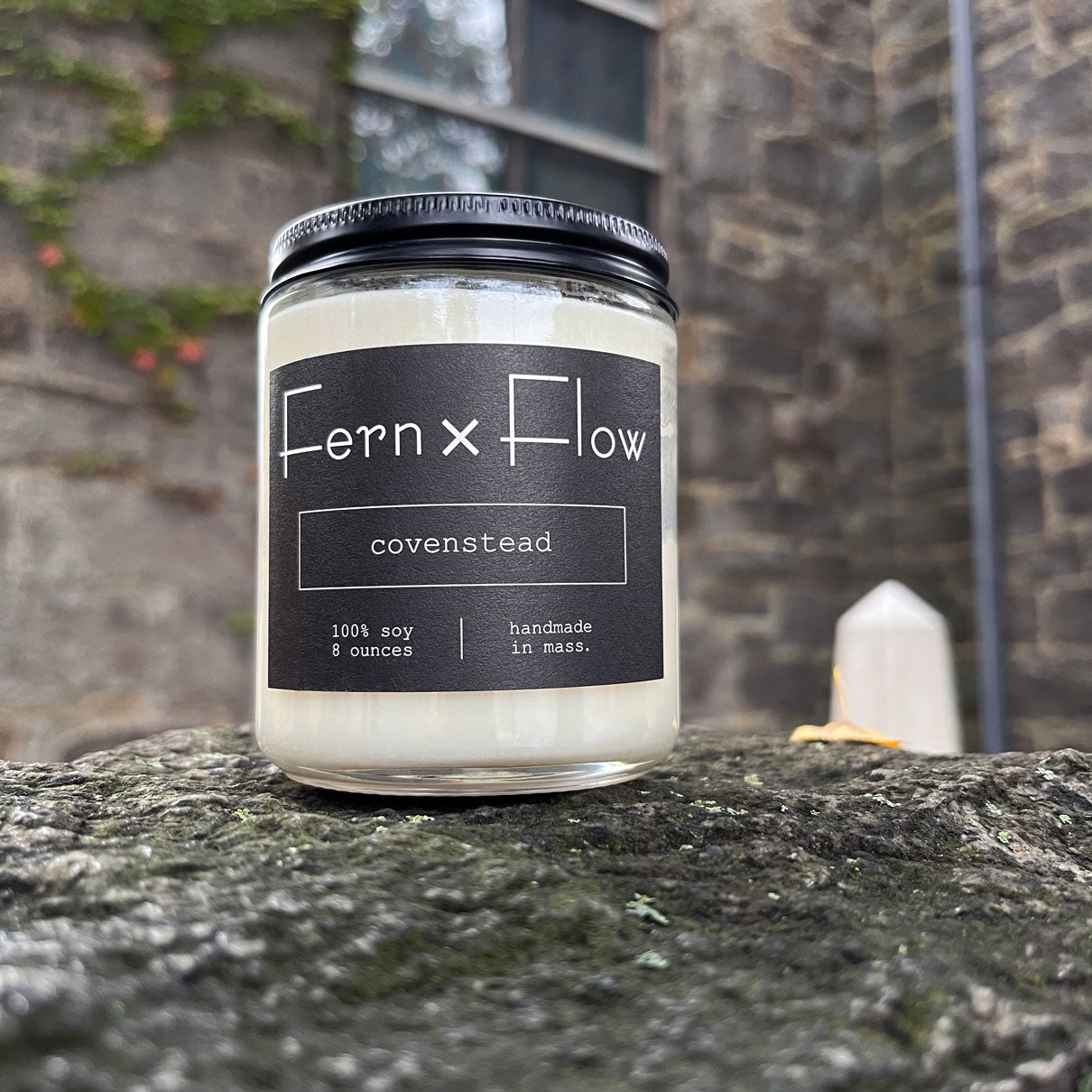 Fern x Flow Covenstead Halloween scented soy candle in front of an old church covered in vines in Salem MA