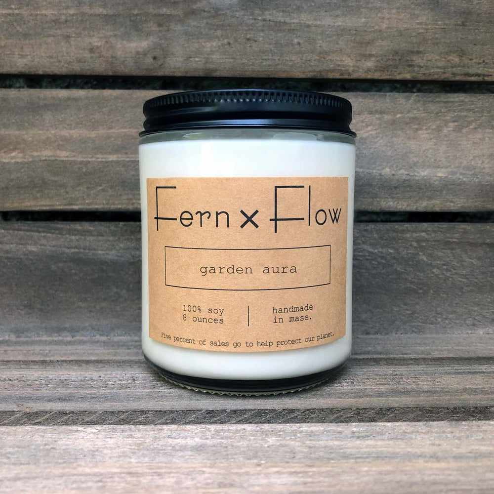 Eight-ounce Fern x Flow Garden Aura scented soy candle against a weathered wooden background.