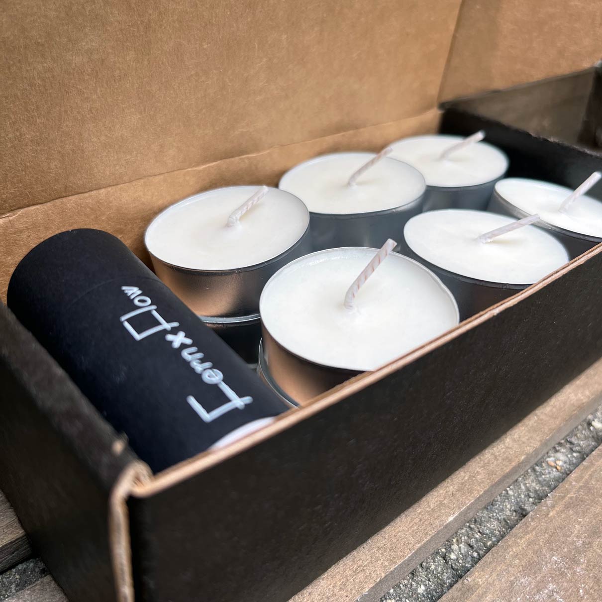 Inside view of Soy Tealight Package from Fern x Flow with black, barrel safety matches and 18 tealight candles neatly stacked inside the matte, black box.
