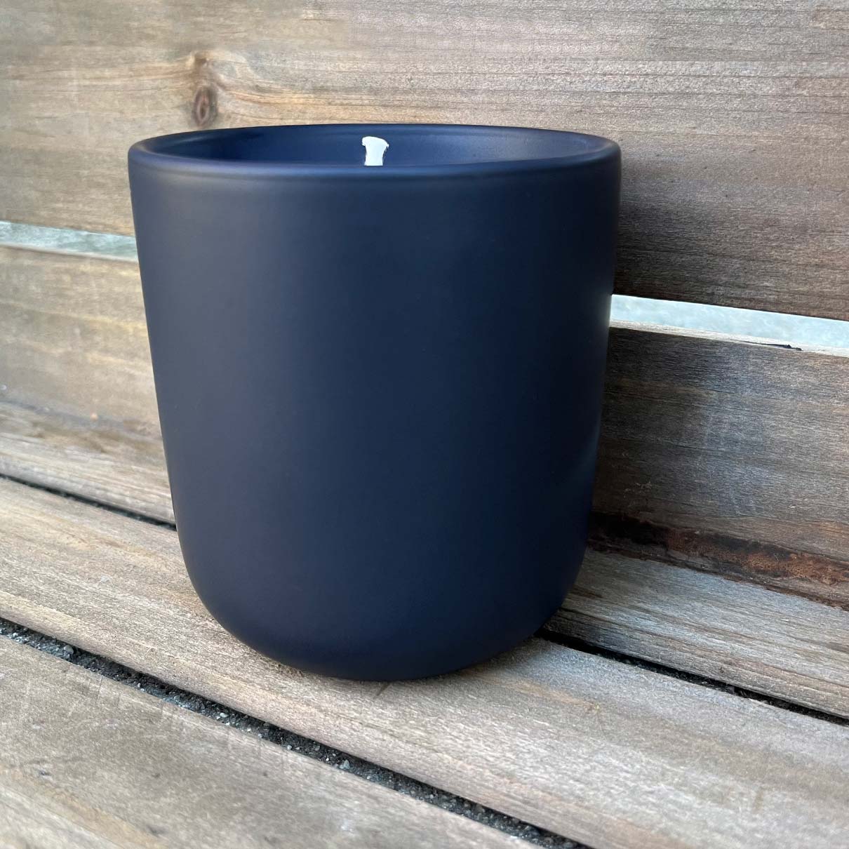 Fern x Flow 10oz hand-poured, 100% soy candle in a modern, matte black ceramic tumbler against a weathered wooden background.