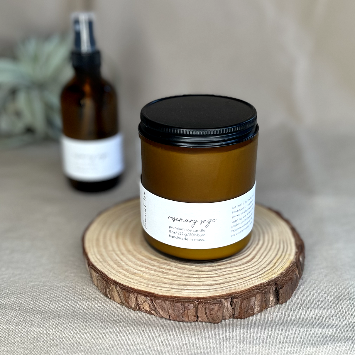 Fern x Flow Rosemary Sage vegan soy candle and air + linen spray fragrance bundle on a rustic wooden riser.