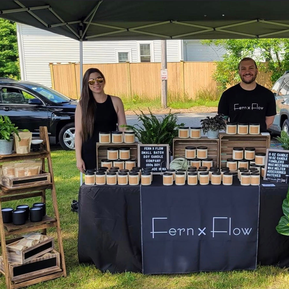 Fern x Flow Soy Candle Company owners Haley and Joe Wing in front of their soy candle display at the Wilmington Farmers Market