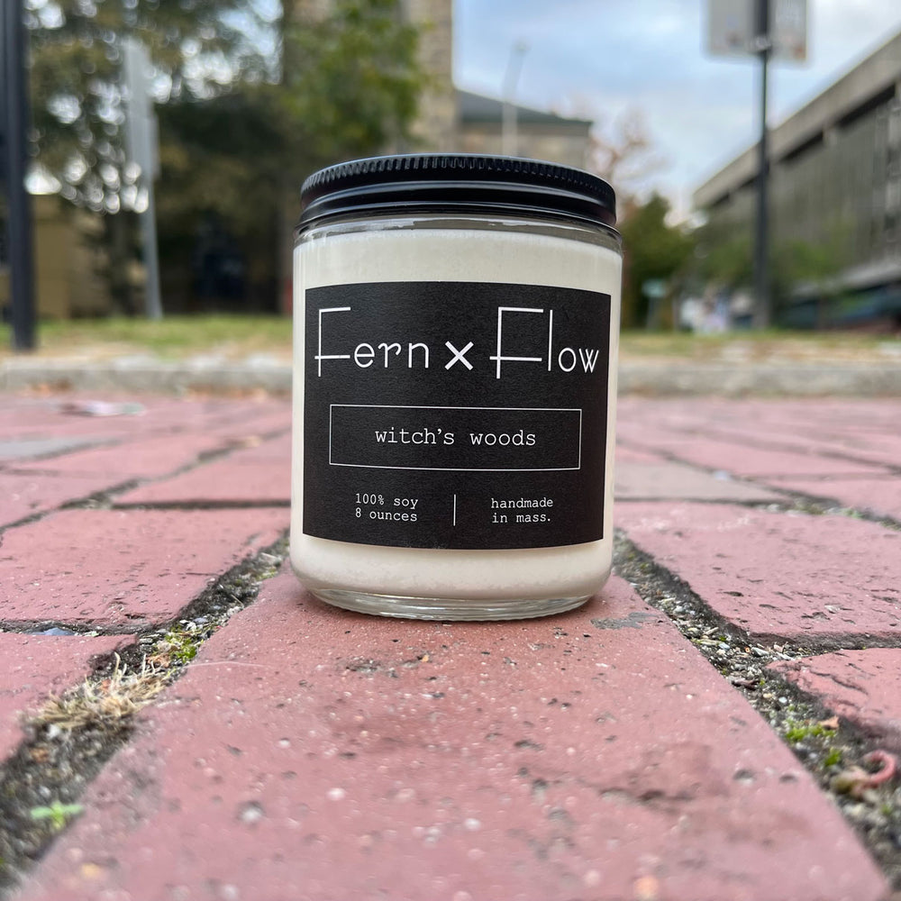 Fern x Flow Witch's Woods Halloween scented soy candle against brick road in in Salem MA