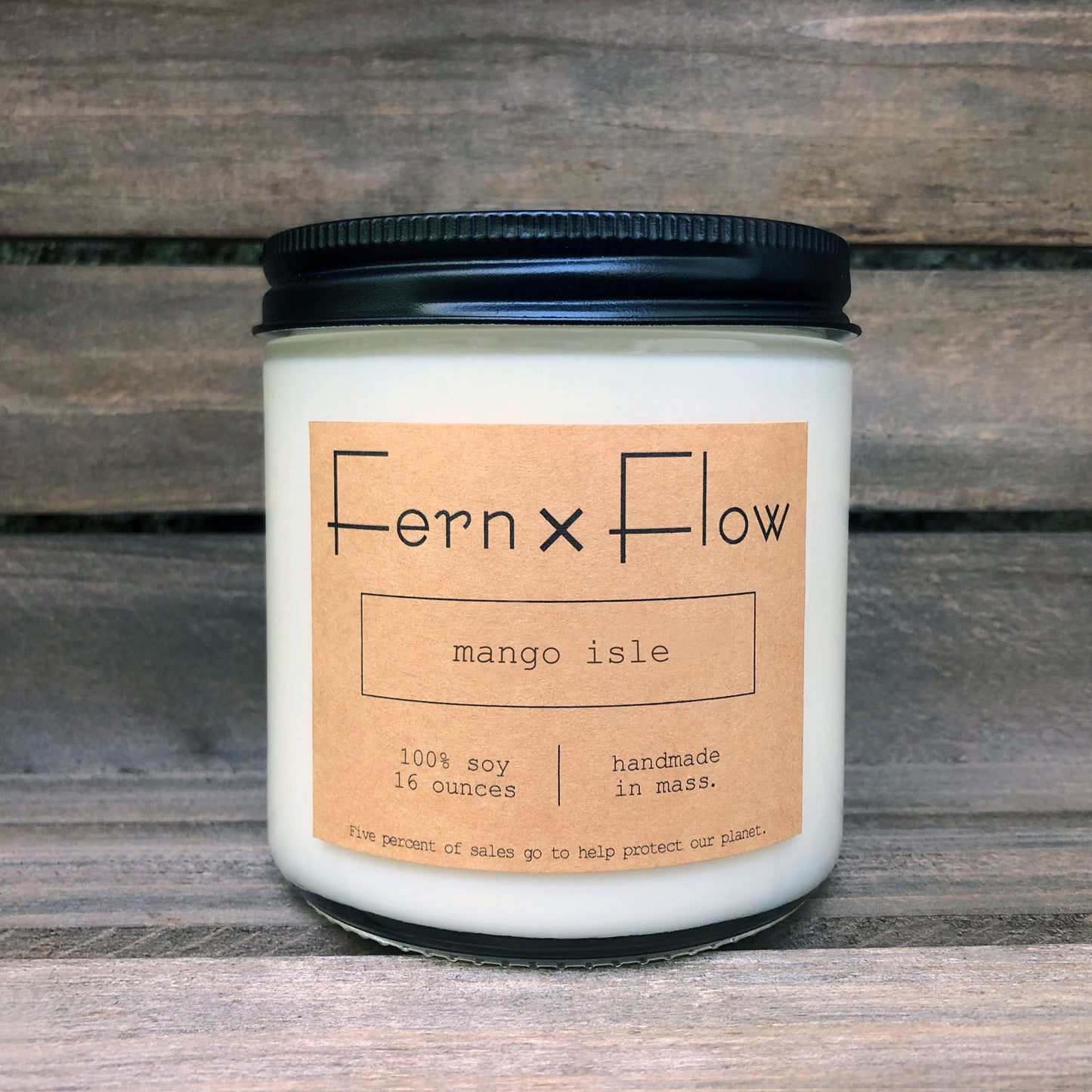 Sixteen-ounce Fern x Flow Mango Isle scented soy candle against a weathered, wooden crate.