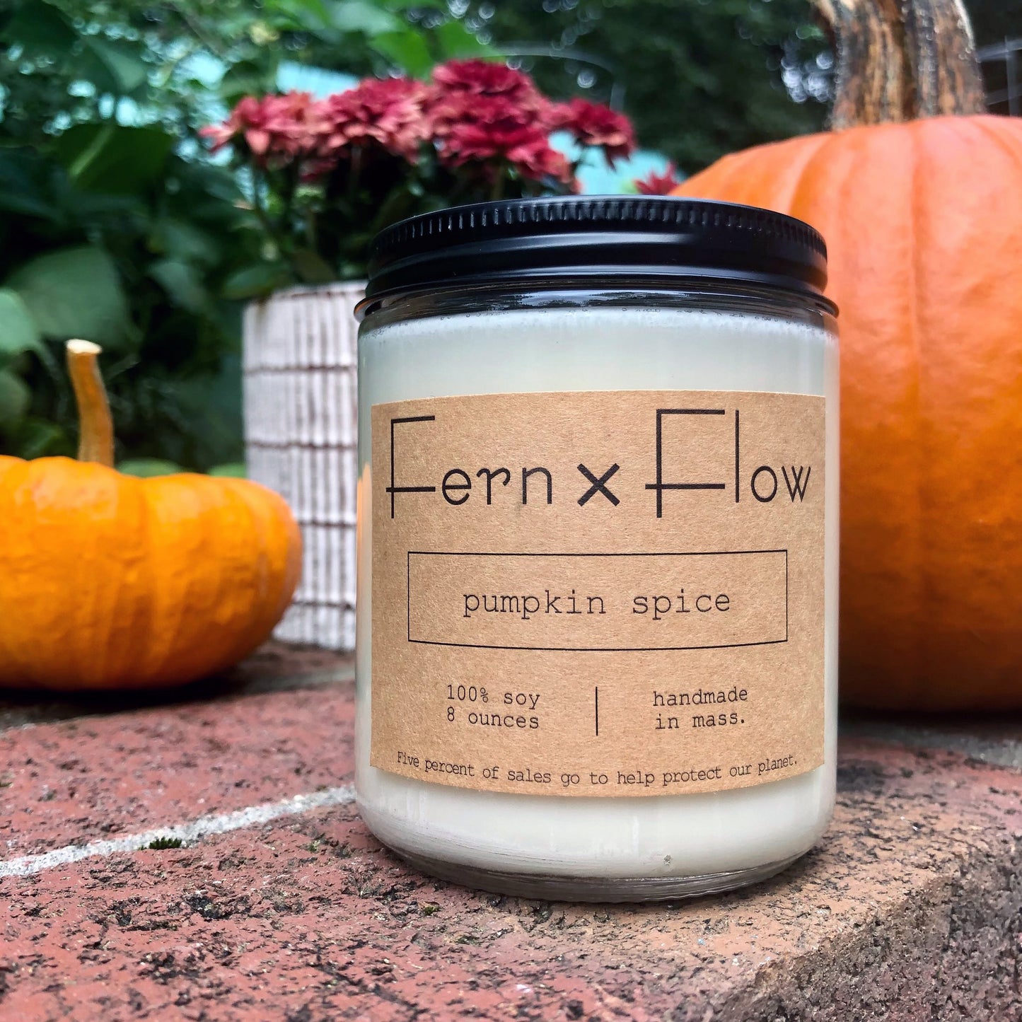 
                  
                    Fern x Flow Pumpkin Spice soy candle on a brick wall, in front of several pumpkins and red mums.
                  
                