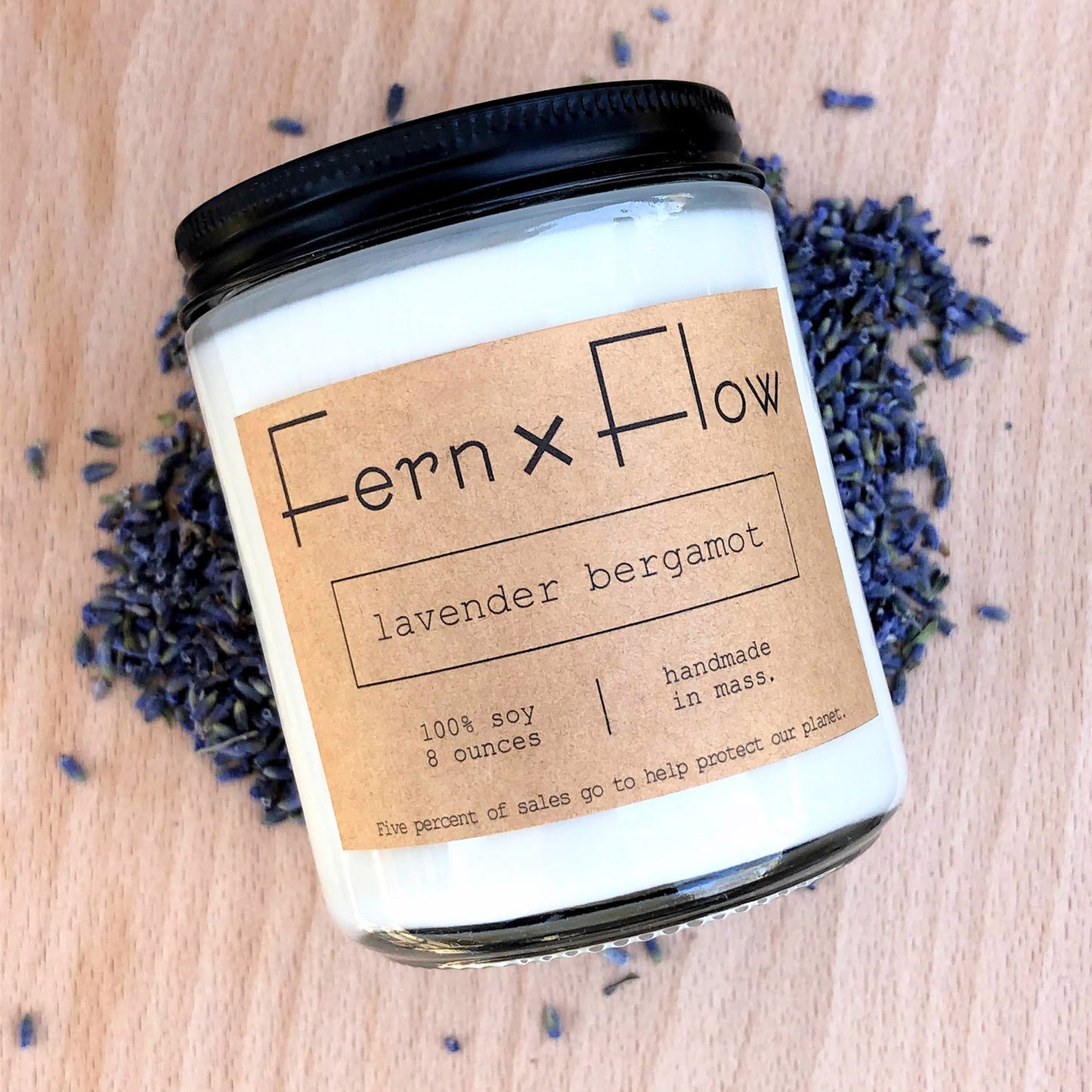 
                  
                    Eight-ounce Fern x Flow Lavender Bergamot scented soy candle on top of a pile of dried lavender buds, with a light wooden background.
                  
                