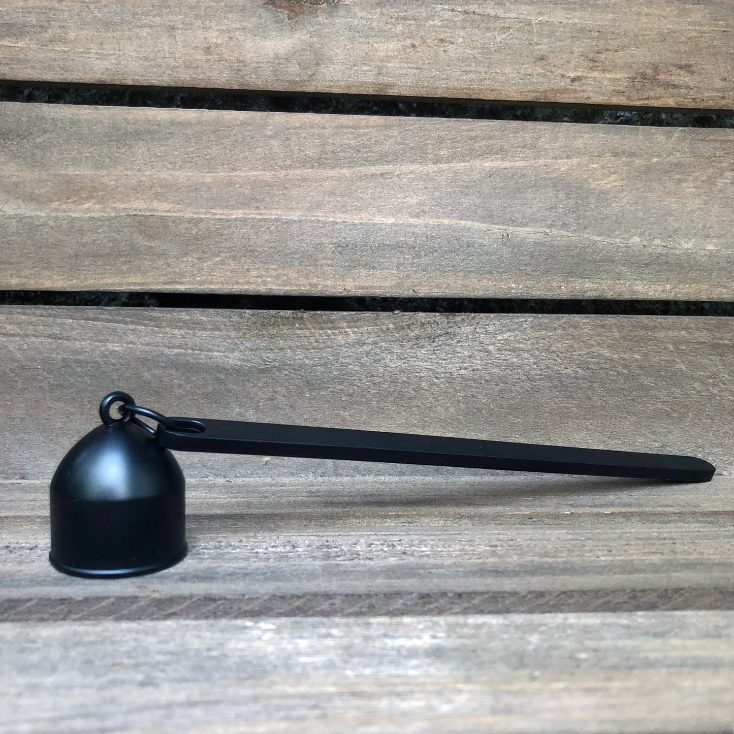 
                  
                    Matte black candle snuffer against weathered wood background.
                  
                