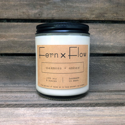 Eight-ounce Fern x Flow Oakmoss + Amber scented soy candle against a weathered, wooden crate.