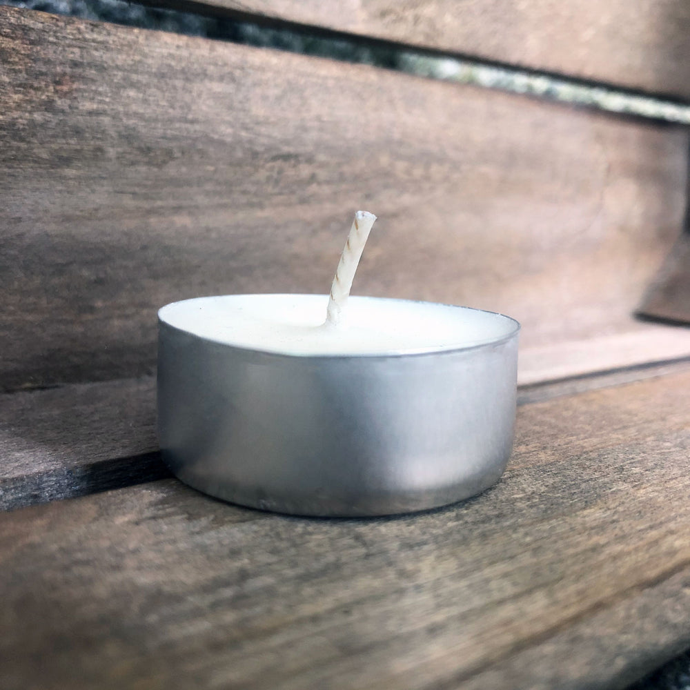 Individual soy wax tealight from Fern x Flow against a weathered, wooden background.