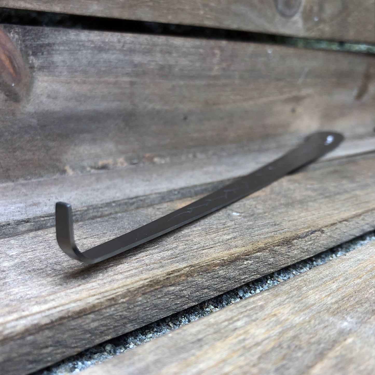 Stainless steel, smokeless candle wick dipper against a weathered wooden crate.